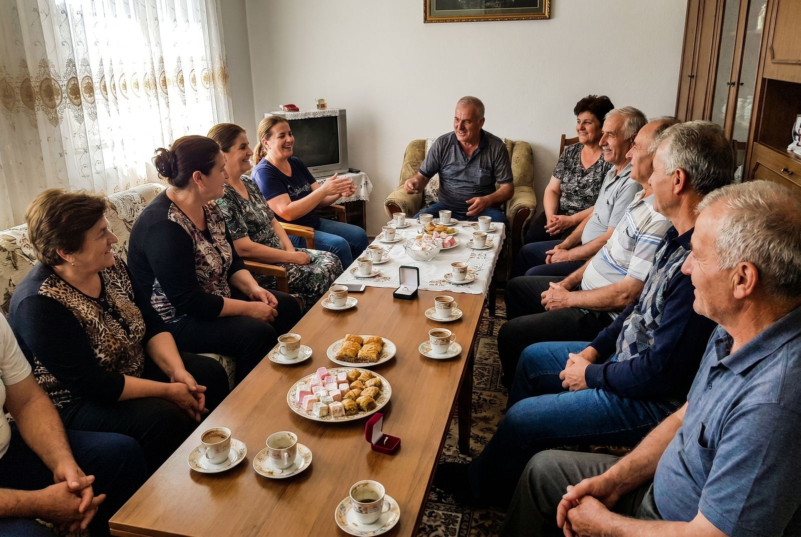 Zwei albanische Familien sitzen bei der Fejesa an einem gedeckten Tisch zusammen