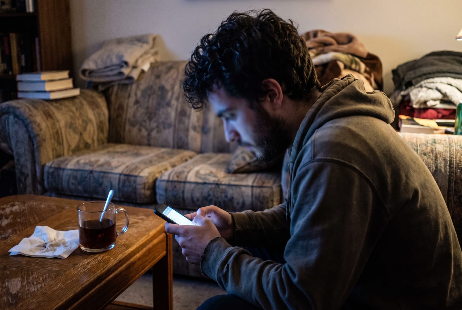 Junger Mann scrollt abends auf dem Sofa durch eine Dating-App auf dem Handy